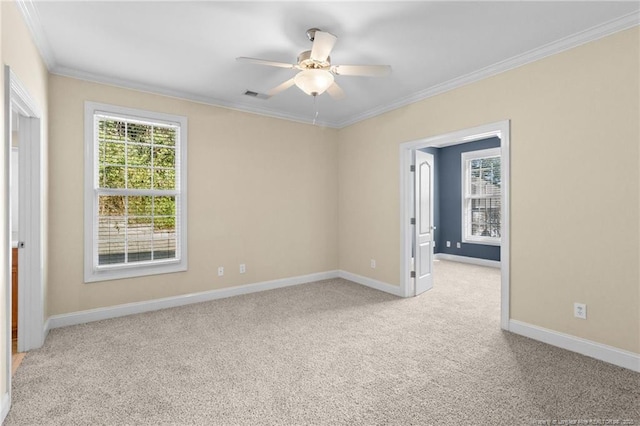 spare room with ornamental molding, a wealth of natural light, light colored carpet, and visible vents