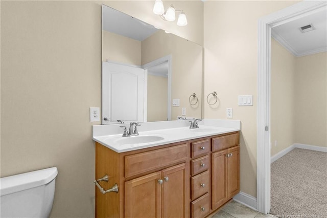 bathroom with visible vents, double vanity, a sink, and toilet