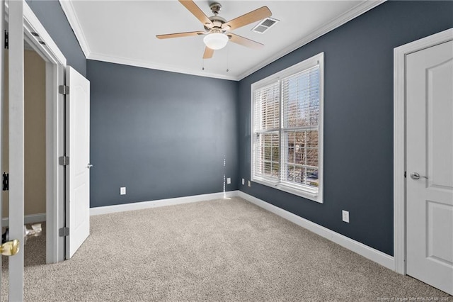 unfurnished bedroom with carpet floors, a ceiling fan, visible vents, baseboards, and ornamental molding