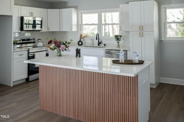 kitchen with stainless steel appliances, light countertops, dark wood-type flooring, white cabinetry, and a sink