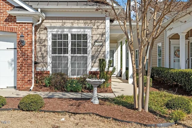 entrance to property with a porch, a garage, and brick siding