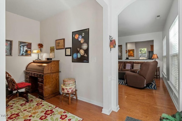 living area with visible vents, wood finished floors, baseboards, and arched walkways