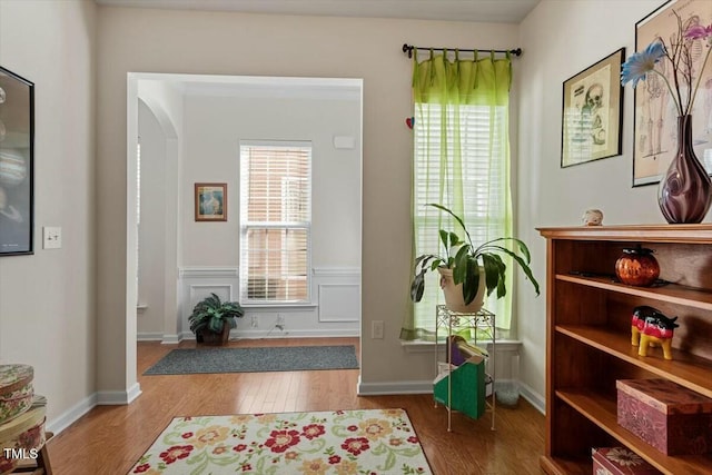 interior space with arched walkways, wood finished floors, and a decorative wall