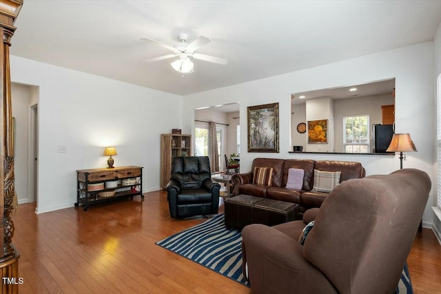 living room with hardwood / wood-style floors, a ceiling fan, and baseboards