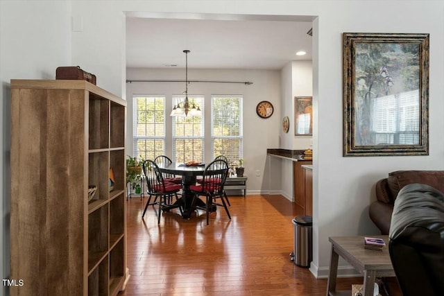 dining area featuring a chandelier, baseboards, and dark wood finished floors