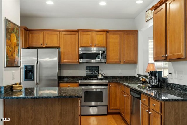 kitchen featuring dark stone countertops, brown cabinets, and appliances with stainless steel finishes