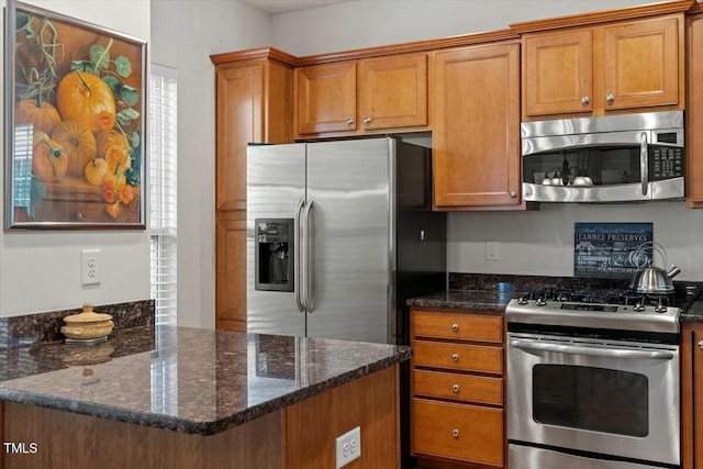 kitchen with dark stone countertops, stainless steel appliances, and brown cabinetry