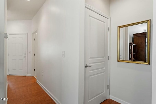 corridor featuring baseboards and wood finished floors