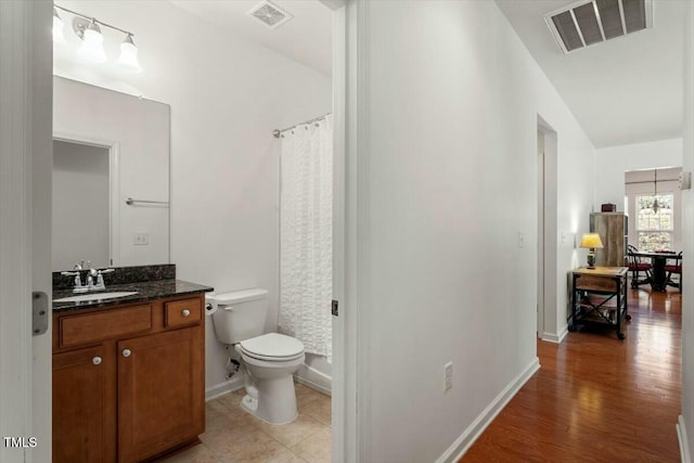 bathroom with visible vents, toilet, vanity, and wood finished floors