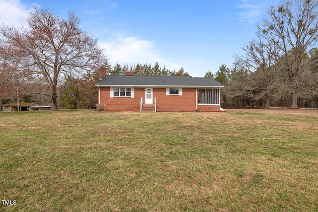 single story home with brick siding, a chimney, and a front lawn