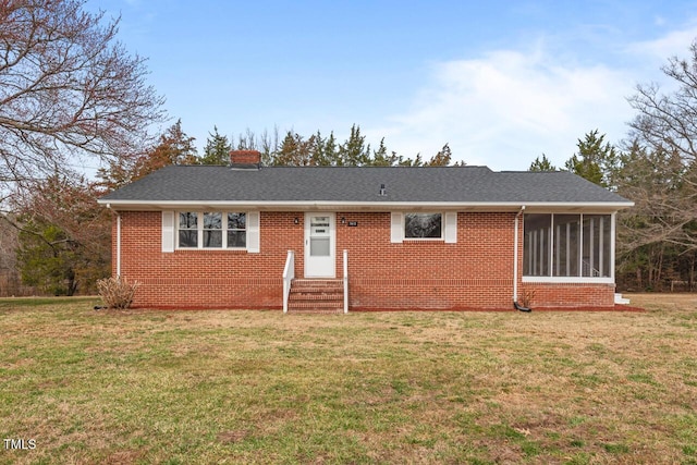 single story home with entry steps, a sunroom, brick siding, and a front lawn