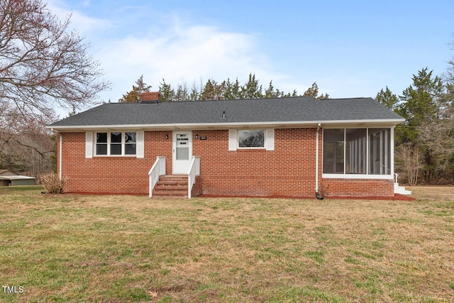 ranch-style house with entry steps, a chimney, a front lawn, and brick siding