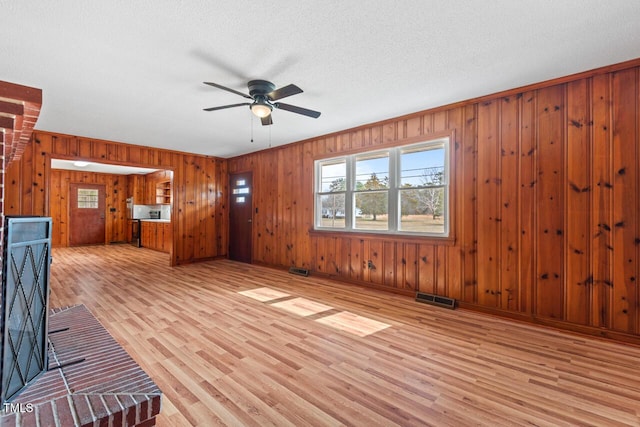 unfurnished living room with light wood finished floors, a textured ceiling, visible vents, and a ceiling fan