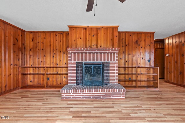 living room with crown molding, a ceiling fan, a fireplace, and wood finished floors