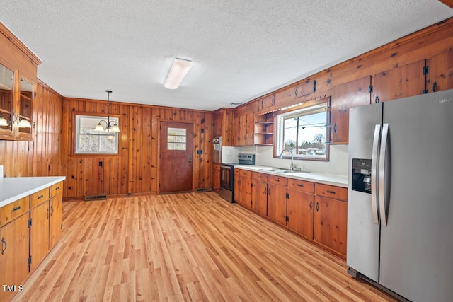 kitchen with a sink, light countertops, appliances with stainless steel finishes, and open shelves