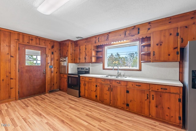 kitchen featuring brown cabinets, appliances with stainless steel finishes, open shelves, and a sink