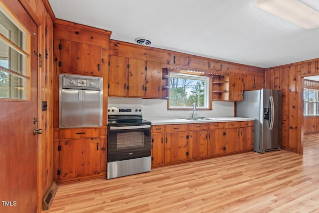 kitchen featuring a sink, visible vents, appliances with stainless steel finishes, open shelves, and brown cabinetry