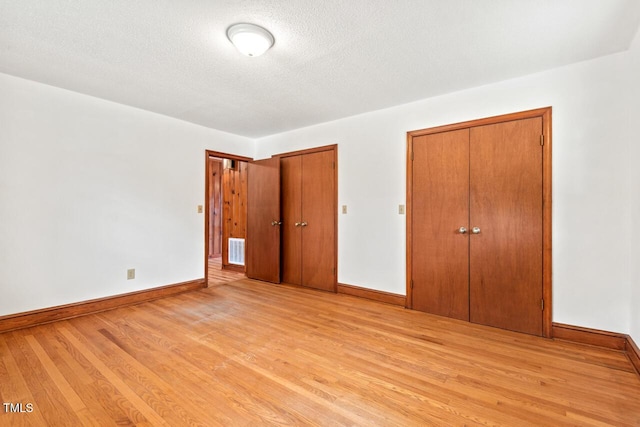 unfurnished bedroom featuring baseboards, visible vents, and light wood-style floors