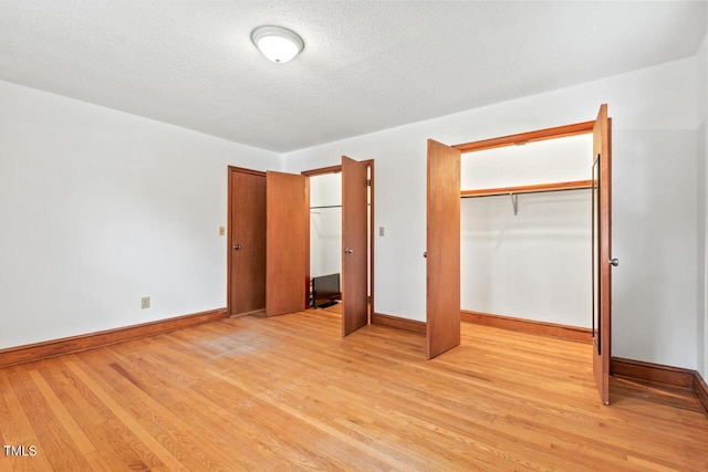 unfurnished bedroom featuring a textured ceiling, light wood finished floors, and baseboards