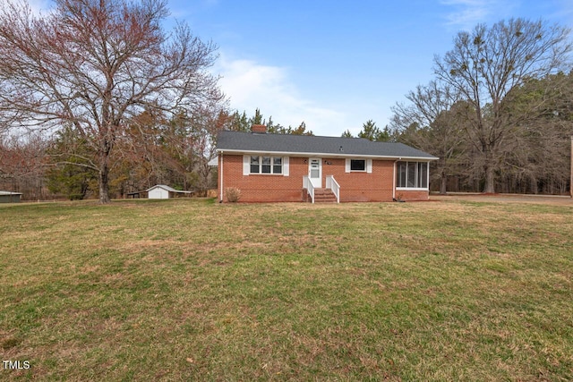 ranch-style home featuring a front lawn, an outdoor structure, and brick siding