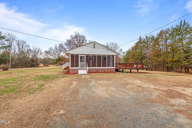 view of front of home featuring a sunroom, a front lawn, and brick siding