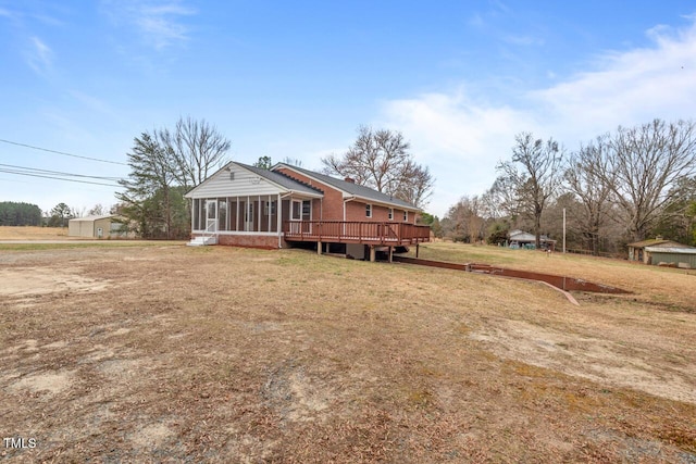 rear view of property with a sunroom, brick siding, a lawn, and a deck