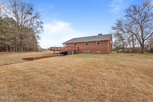 back of property featuring a yard, a wooden deck, a chimney, and brick siding