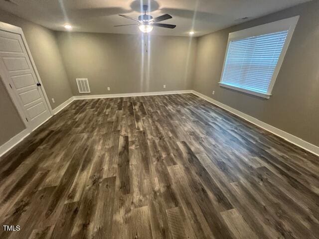 spare room featuring visible vents, a ceiling fan, dark wood-type flooring, and baseboards