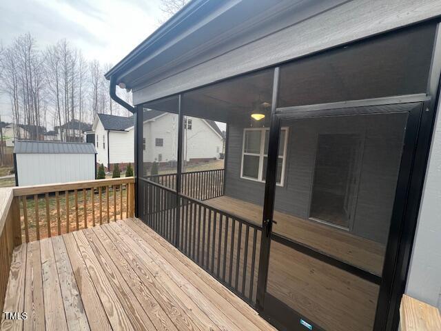 wooden terrace with a storage shed, an outbuilding, and a sunroom