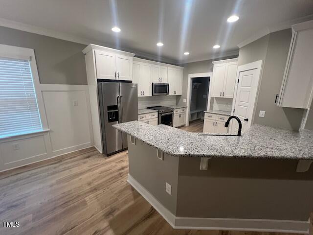 kitchen featuring a sink, a peninsula, ornamental molding, and stainless steel appliances