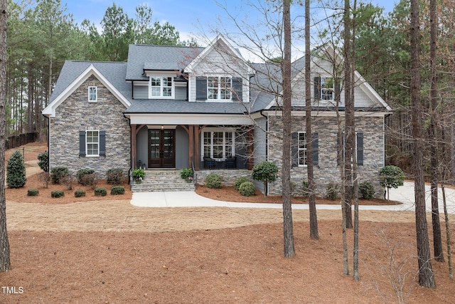 craftsman-style house featuring stone siding, french doors, roof with shingles, and a porch