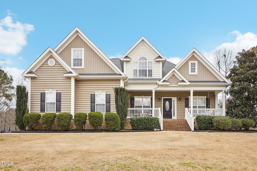 craftsman-style house featuring covered porch, a front lawn, and board and batten siding