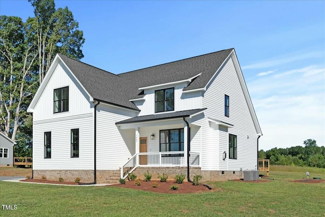 modern farmhouse featuring cooling unit, covered porch, roof with shingles, and a front yard