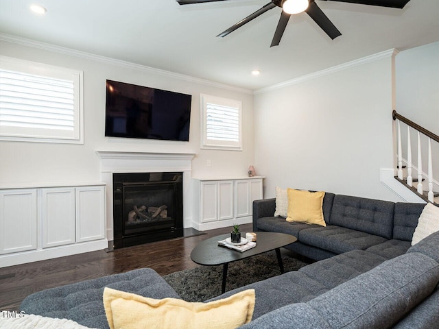 living room featuring a glass covered fireplace, crown molding, and stairs