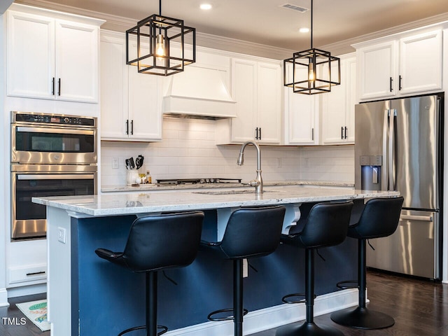 kitchen with stainless steel appliances, white cabinets, custom range hood, and light stone countertops