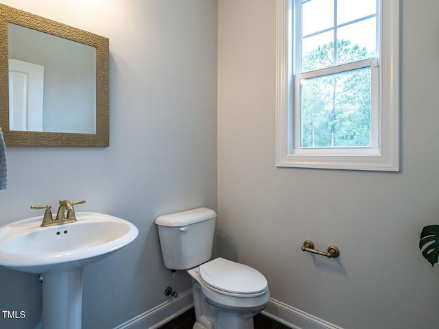 bathroom with plenty of natural light, toilet, and baseboards