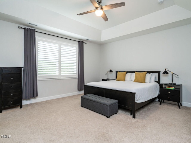 bedroom with baseboards, a raised ceiling, visible vents, and light colored carpet