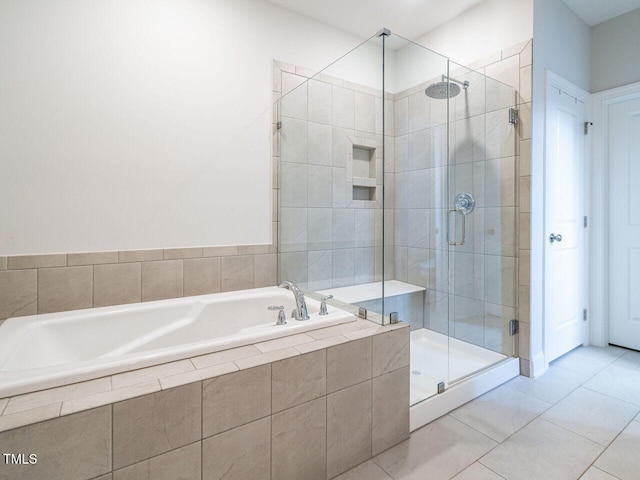 bathroom featuring a bath, a shower stall, and tile patterned flooring