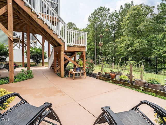 view of patio with a vegetable garden, stairs, and fence