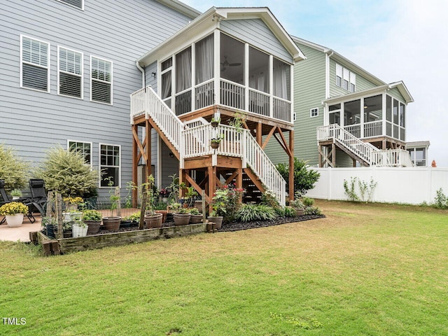 back of property featuring a sunroom, a yard, fence, and stairs