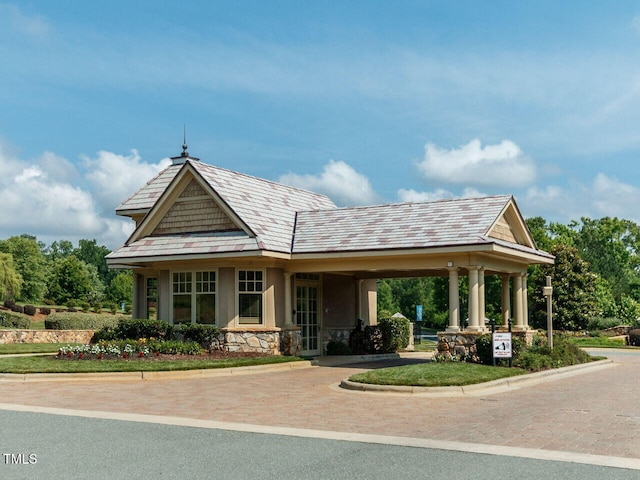 exterior space featuring stone siding, decorative driveway, and stucco siding