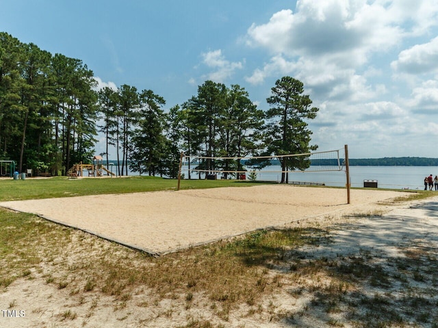 view of property's community with a water view, a lawn, and volleyball court