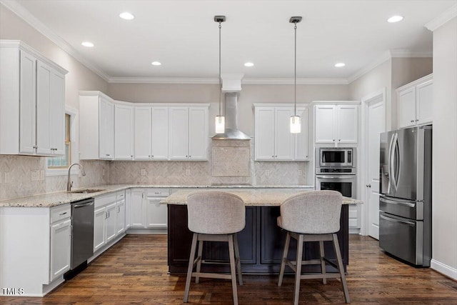 kitchen with a kitchen island, appliances with stainless steel finishes, wall chimney range hood, white cabinetry, and a sink