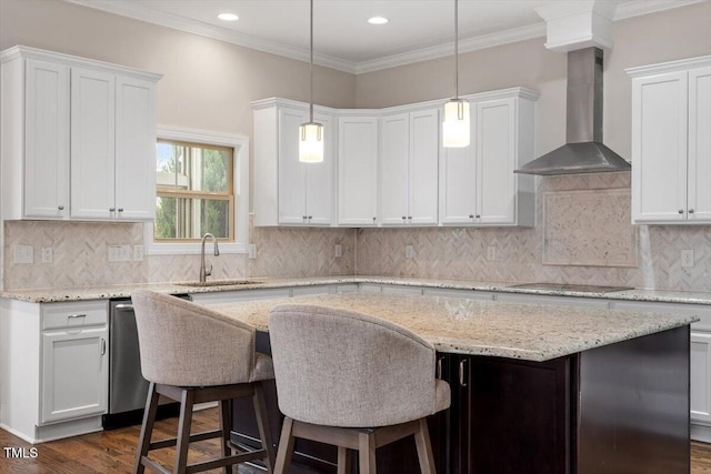 kitchen featuring wall chimney exhaust hood, a kitchen island, ornamental molding, black electric stovetop, and a sink