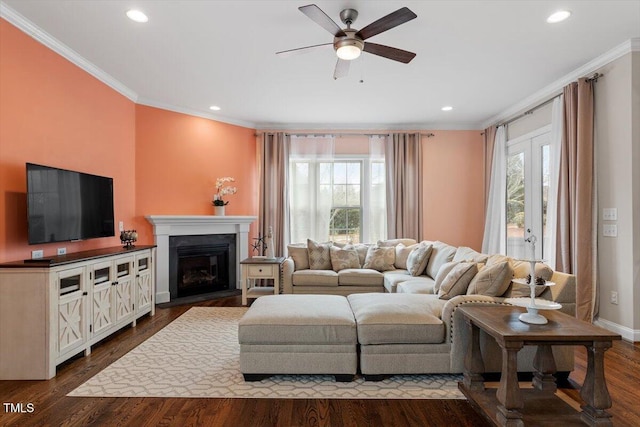 living room with recessed lighting, dark wood-style flooring, baseboards, a glass covered fireplace, and crown molding