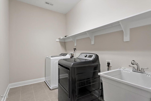 clothes washing area featuring washing machine and clothes dryer, visible vents, a sink, laundry area, and baseboards