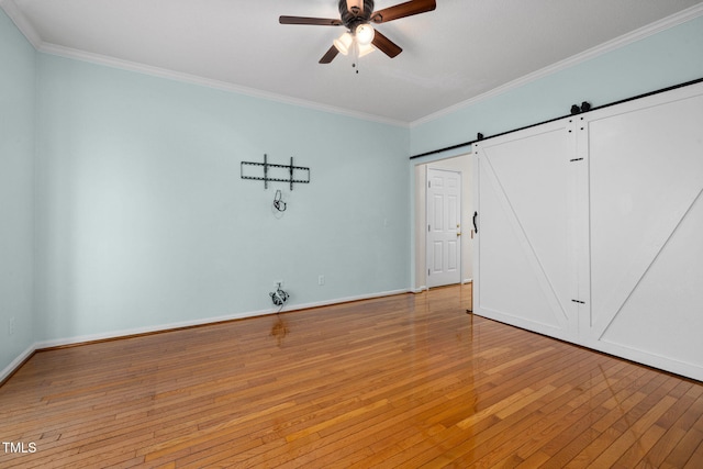 unfurnished bedroom featuring a barn door, light wood-style flooring, a ceiling fan, baseboards, and crown molding