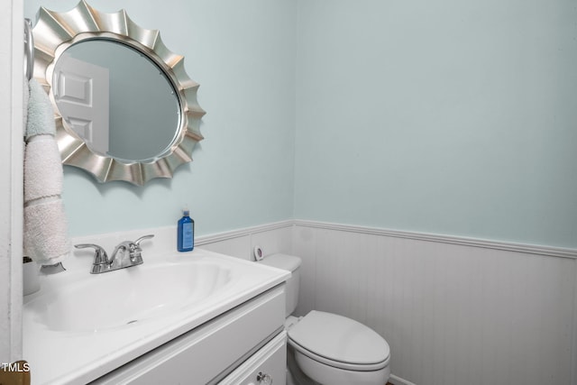 bathroom featuring toilet, wainscoting, and vanity