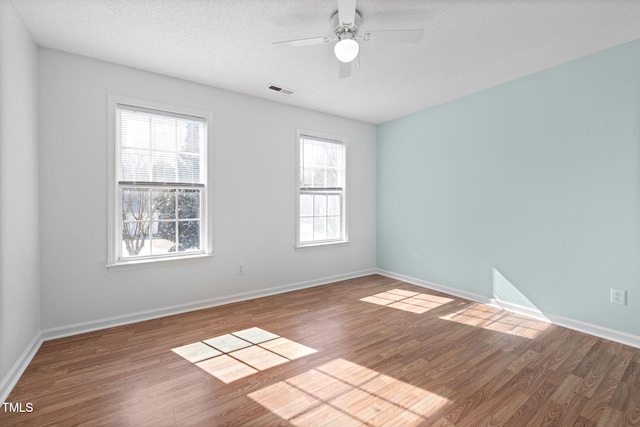 spare room featuring a textured ceiling, baseboards, and wood finished floors