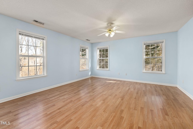 spare room featuring light wood-type flooring, visible vents, and a wealth of natural light